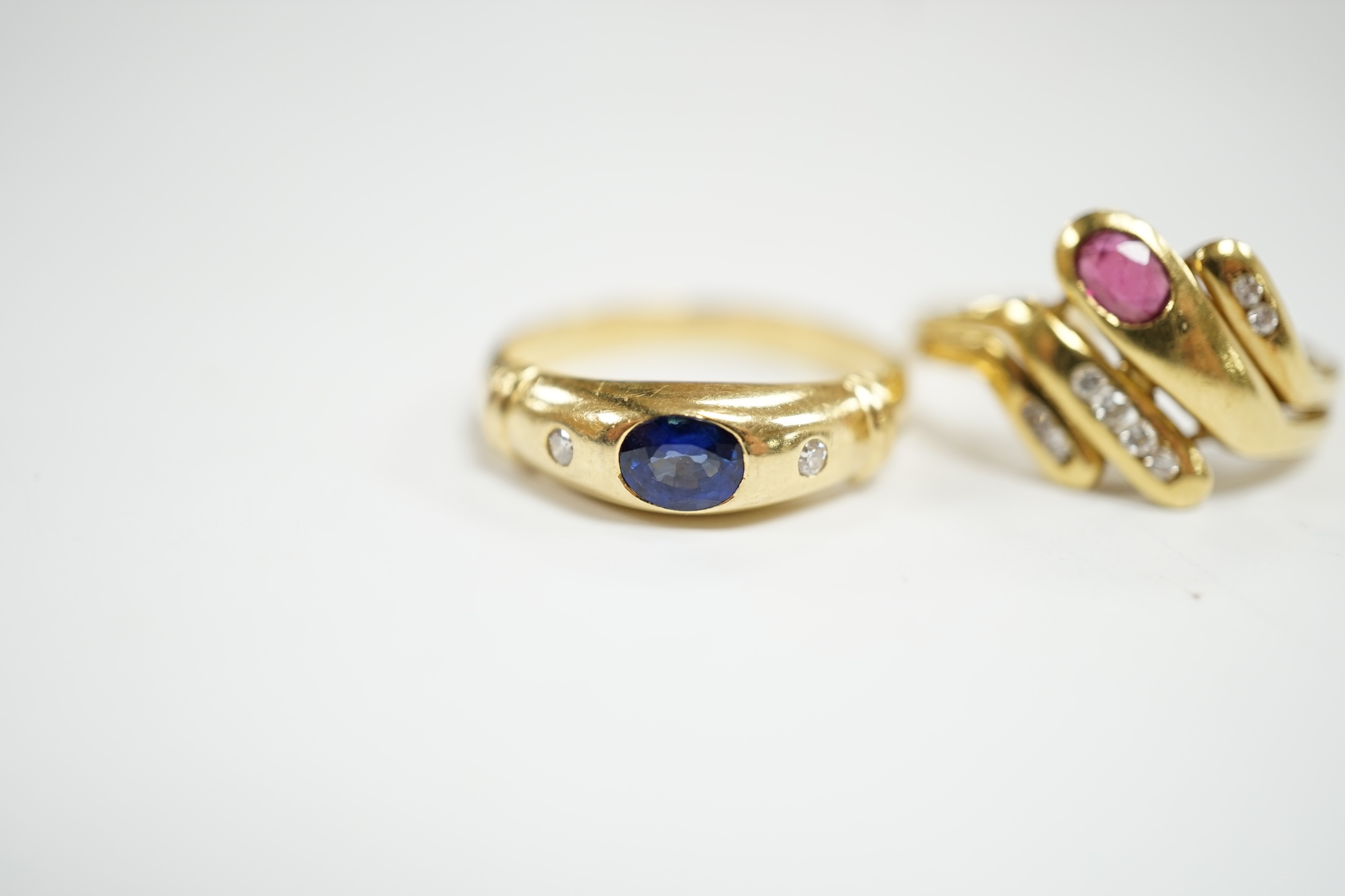 A modern 750 yellow metal and gypsy set single stone sapphire and two stone diamond set ring, size N, together with an Italian 750 yellow metal, ruby and diamond cluster set dress ring, size , gross weight 6.8 grams.